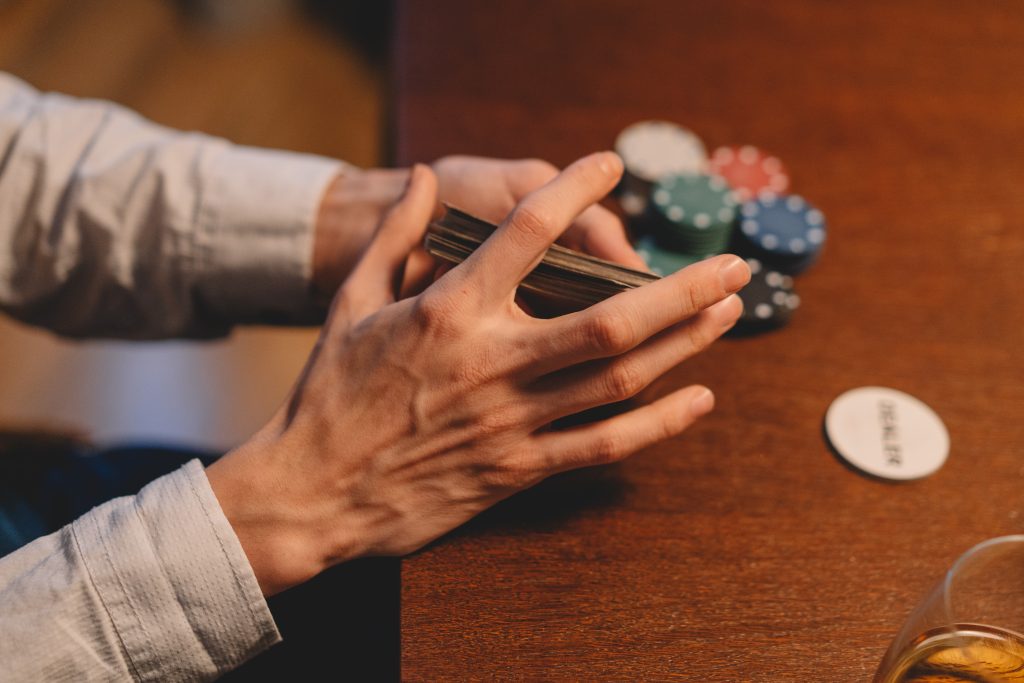 person holding cards, casino chips on a wooden table
