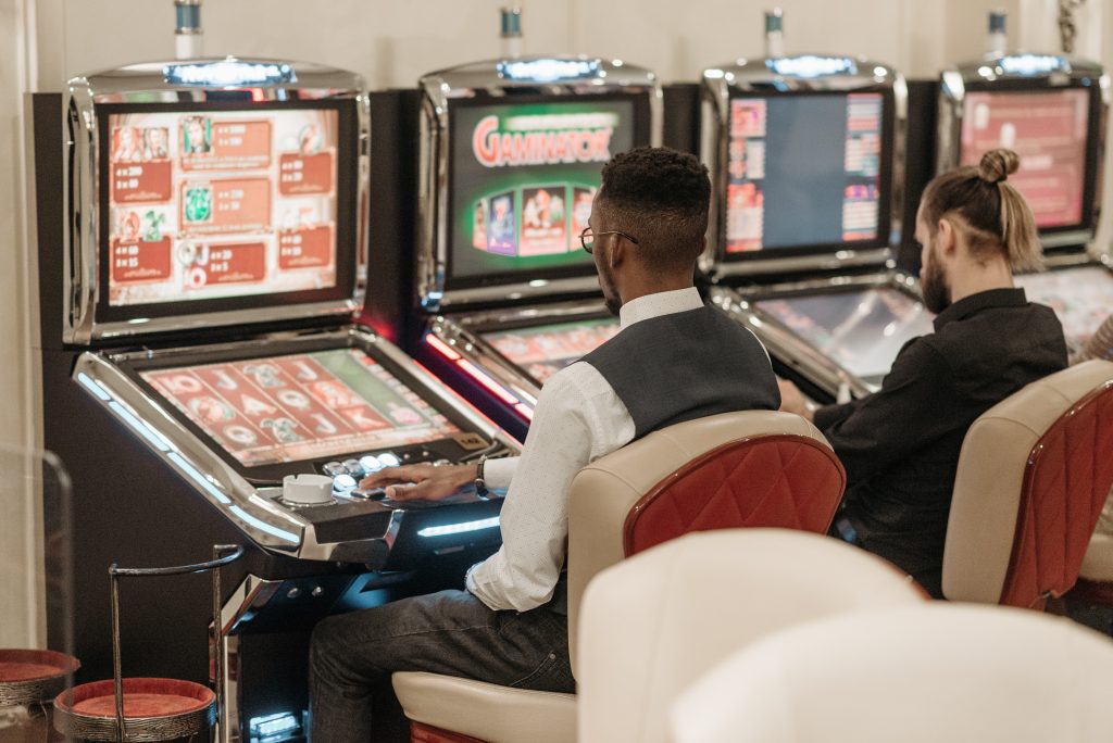 two men sitting in front of a row of slot machines
