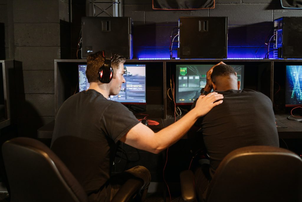 two men in black shirt playing online games, one player comforting another