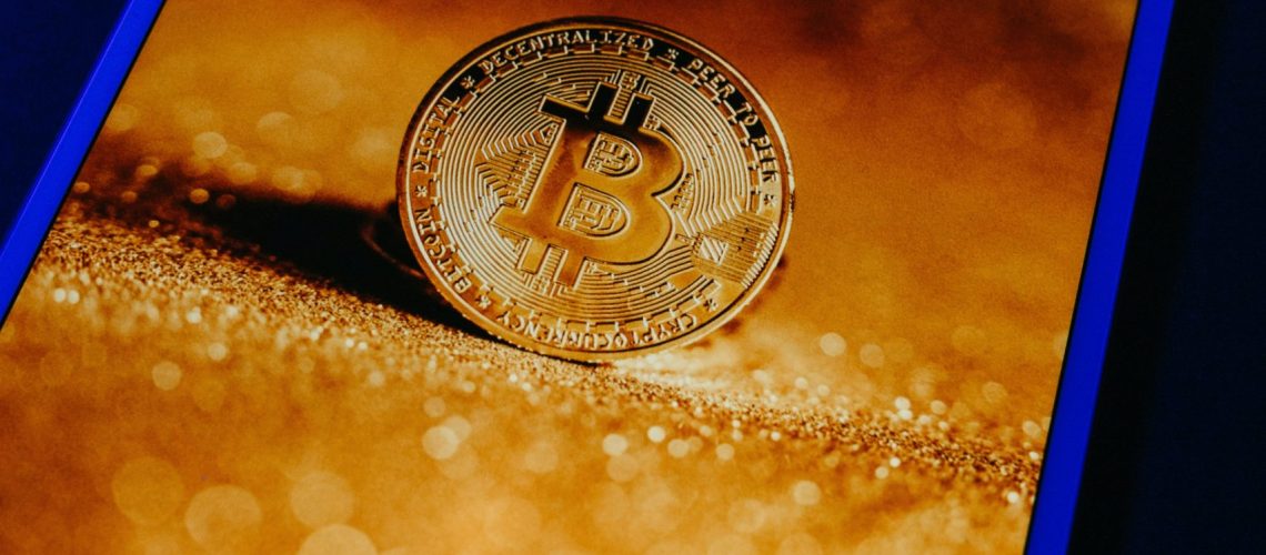 bitcoin display on an ipad, with a background of shimmering gold sand