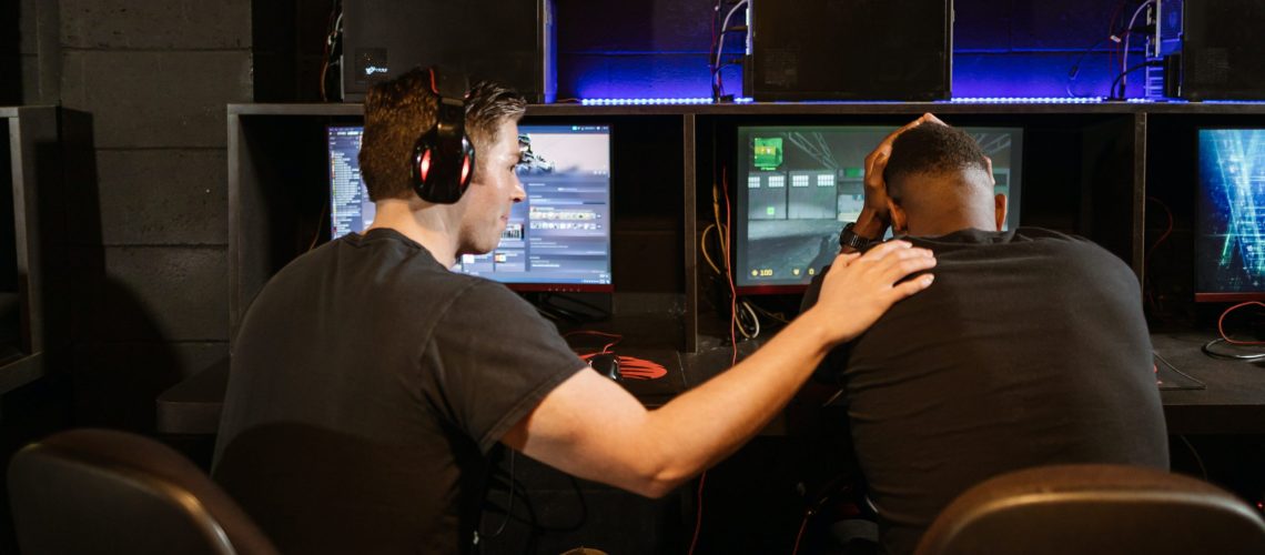two men in black shirt playing online games, one player comforting another