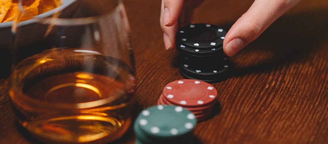 person holding poker chips, casino chips aligned in a row on a wooden table